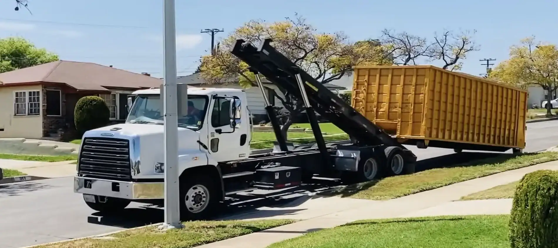 A roll-off truck delivering a 20-yard dumpster to a residential driveway in Amarillo, TX.