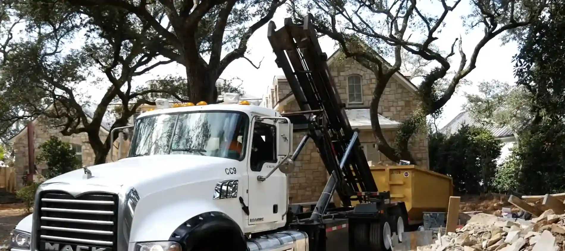 A roll-off dumpster being emptied at a landfill, loaded with demolition debris.
