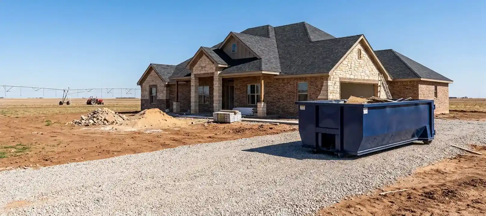 A roll-off dumpster at a new home under construction near Bushland, TX, with farmland nearby.