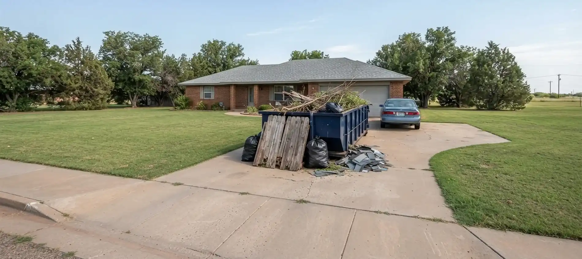 A roll-off dumpster at an established brick ranch home with mature trees in Panhandle, TX.