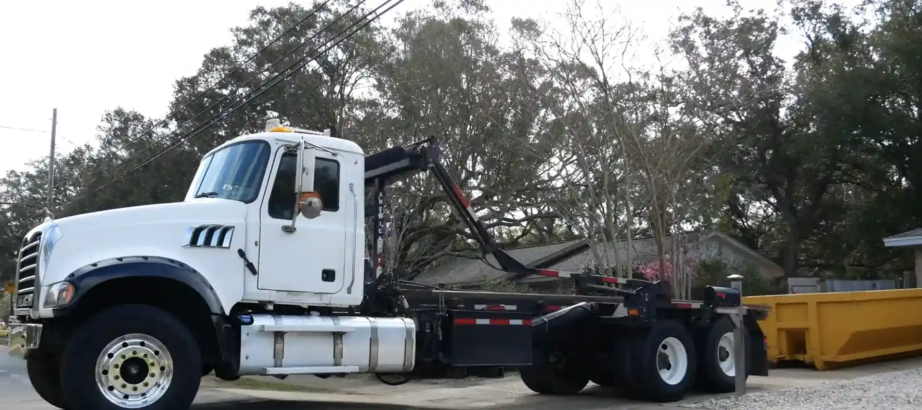 A roll-off dumpster positioned at a large stone home during a cleanout and debris removal project.