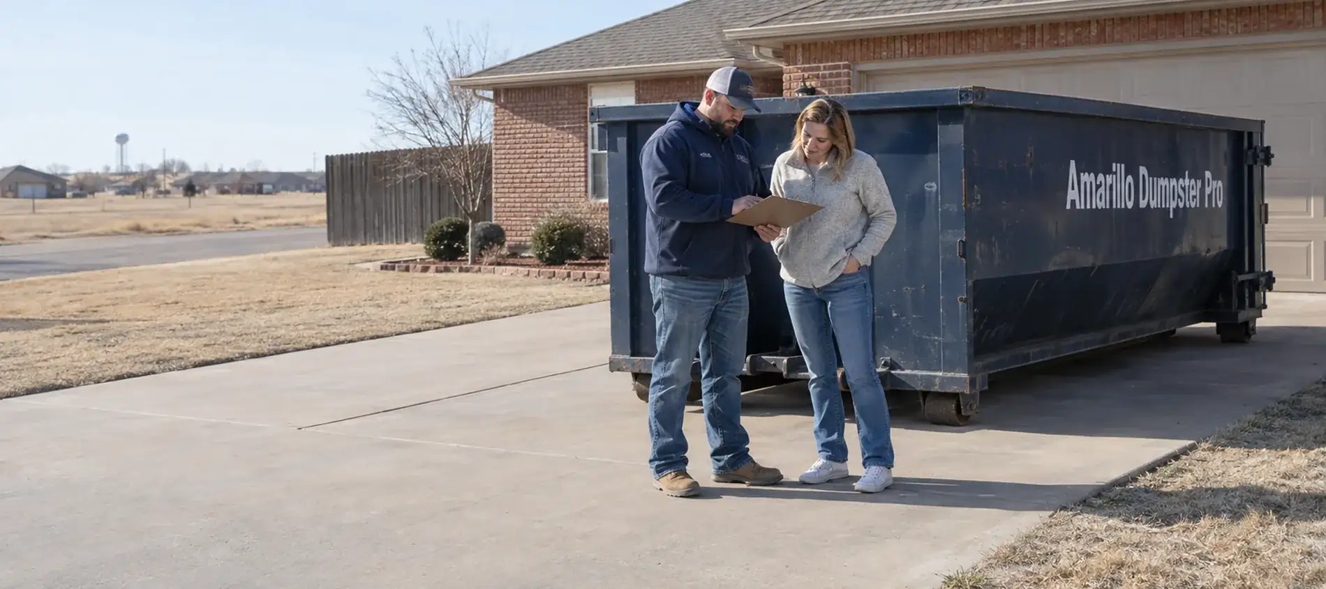 An Amarillo Dumpster Pro driver reviewing pricing on a clipboard with a customer by a dumpster.