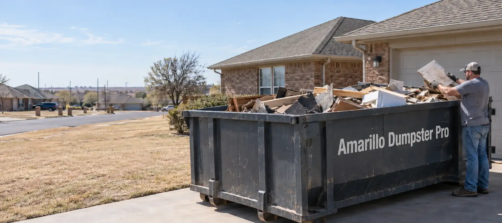 A man loading debris into a branded roll-off dumpster in a residential driveway.