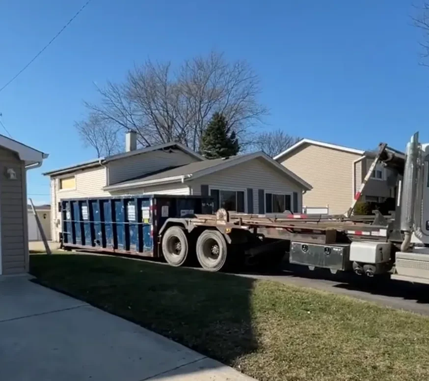 A roll-off dumpster placed in a residential driveway, ready to load
