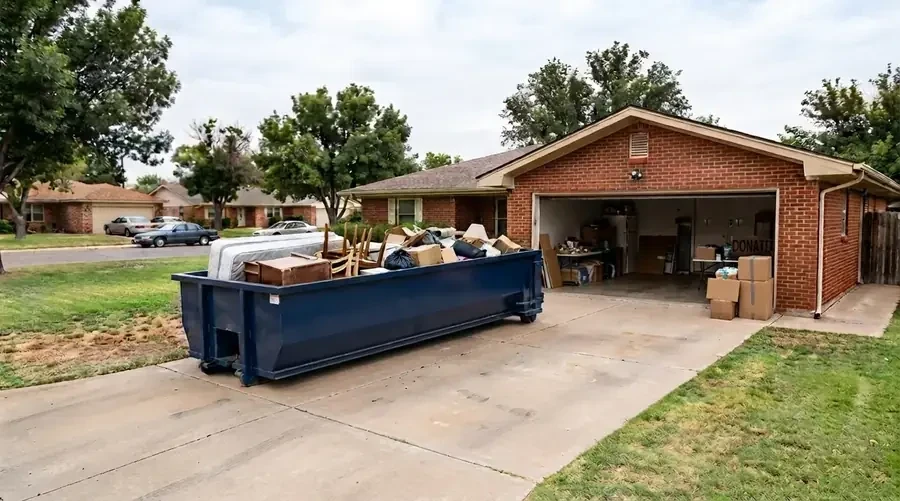 A dumpster loaded with furniture and boxes during an estate cleanout, donation area nearby.
