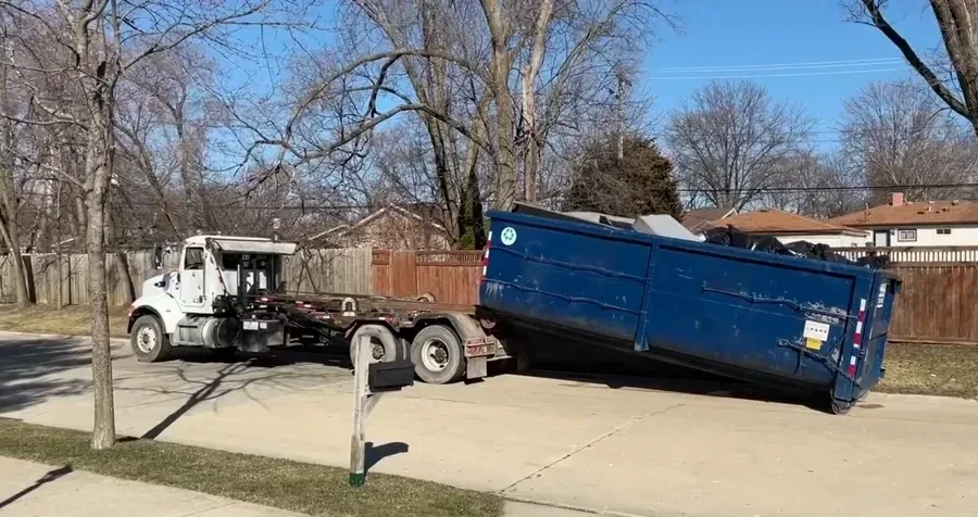 A loaded roll-off dumpster on a residential driveway, ready for pickup