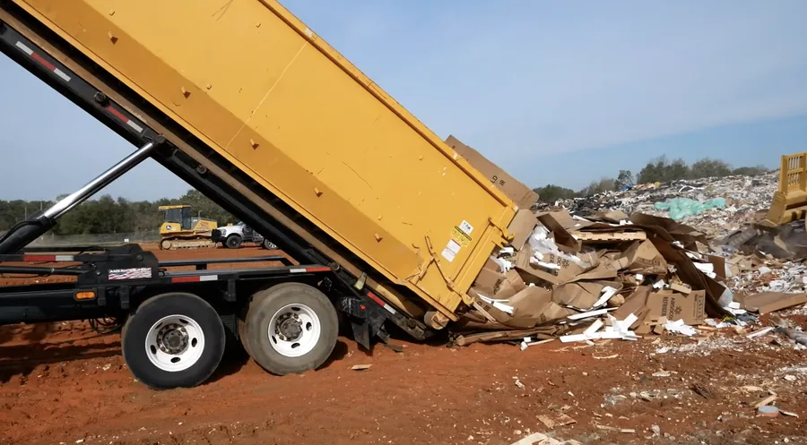 A roll-off truck dumping debris at the landfill, with a loader working nearby