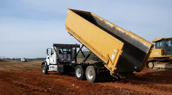 A dump truck tipping a load at the City of Amarillo Landfill, with a bulldozer working the pile.