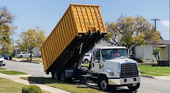 A roll-off dumpster being lowered off the truck, flat-rate delivery with no separate fee.